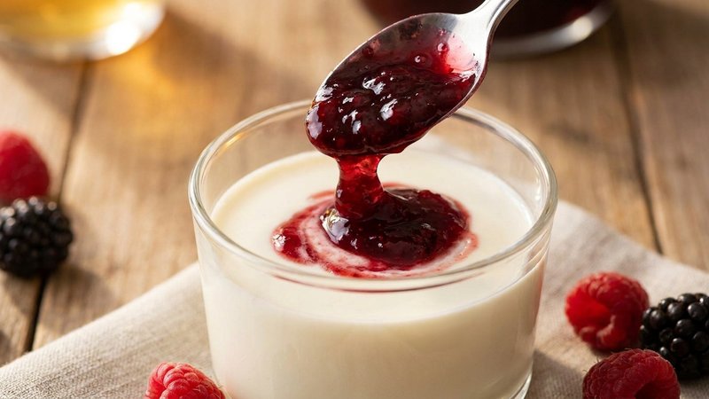 mermelada de fresa siendo servida sobre vasitos de crema